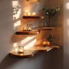 three shelves with candles and some flowers on them next to a wall mounted candle holder