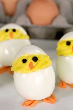 three eggs with faces painted on them sitting in front of an egg carton