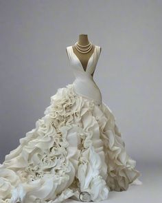 a white wedding dress with ruffled layers and a halter neckline on display