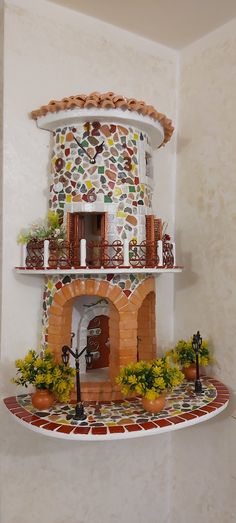 this is a fake house made out of clay and ceramic tiles with flowers on the shelf