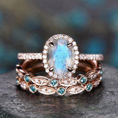 two wedding rings with an aqua and white topazte stone in the center, set on a rock