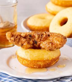 a fried chicken sandwich on top of a donut with honey and syrup in the background