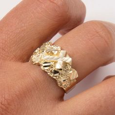 a close up of a person's hand wearing a gold ring with flowers on it