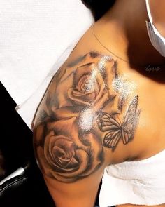 a close up of a woman's shoulder with flowers and butterflies on her arm