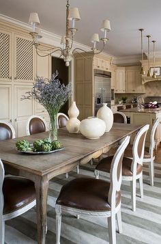 a dining room table with chairs around it and vases on top of the table