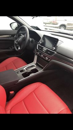 the interior of a car with red leather seats and black dash board, steering wheel and center console