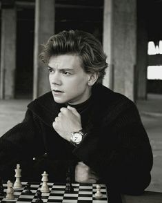 a young man sitting at a chess board