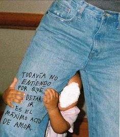 a young child is holding his mom's jeans with writing on the bottom half