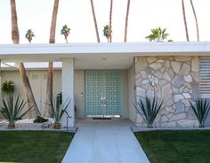 a modern house with palm trees in the front yard and green grass on the lawn