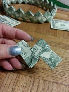 a person holding money in their hand on top of a wooden table next to other dollar bills