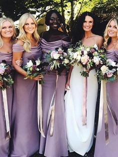 a group of women standing next to each other wearing purple dresses and holding bouquets