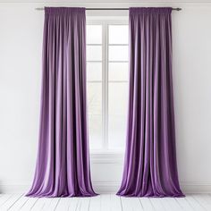 a purple curtain hanging in front of a window with white walls and wooden flooring