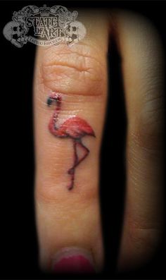 a small flamingo tattoo on the ring finger