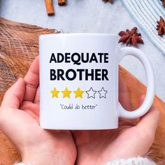 a person holding a coffee mug with five stars on it and the words,'adequate brother could do better '