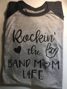 "Band Mom Shirt - Rockin the Band Mom Life Shirt - Band Shirt - Band Life - Marching Band Shirt - Band Love - Crazy Band Mom Description: Are you living that band mom life? How About Rockin it?? Sport this super cute shirt in support of your musically awesome kid! Rockin the Band Mom Life There are two options for this shirt - both are unisex cut! 1. A super soft and comfy 50% cotton, 25% polyester, 25% rayon.. 3/4 sleeve gray with black sleeves. 2. A soft 50% cotton, 50% polyester blend short s Rock And Roll Cotton T-shirt With Band Logo, Cotton Rock And Roll T-shirt With Band Logo, Music-themed Slogan Tops For Concerts, Rock Band Logo T-shirt Relaxed Fit, Rock Band Logo T-shirt In Relaxed Fit, Rock Style Band Logo T-shirt With Relaxed Fit, Rock Style Band Logo T-shirt In Relaxed Fit, Cotton Rock Style T-shirt With Letter Print, Rock Style Cotton T-shirt With Text Print