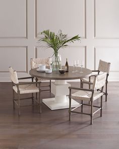 a dining table with chairs around it and a vase on the table next to it