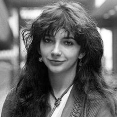 a black and white photo of a woman with long hair wearing a blazer jacket