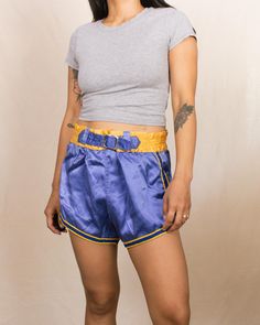 Embrace a piece of athletic history with these vintage 50s/60s basketball shorts from Gold Band. Featuring a stunning blue color with yellow trim detail, these shorts come with a buckle waistband with adjustable holes, giving them a unique and classic look. They feel like a soft rayon blend. Features: Beautiful blue color with yellow trim detail Buckle waistband with adjustable holes Feels like a rayon blend Brand: Gold Band Size: Best fits Small-Medium, for someone with a 26-27" waist Measurements: Waist 27"-28.5" Rise 12.75" Hips 40" Inseam 2.5" Fit Notes: The waistband no longer stretches, and the fabric has no stretch, making them best suited for someone with a small waist-to-hip ratio. The model has a 25" waist and 35" hips, and the shorts were slightly big on her. Condition: The elas Retro Athletic Shorts For Sports, Playful Blue Shorts With Elastic Waistband, Blue Nylon Shorts, Blue Vintage High-waisted Shorts, Retro Blue Athletic Shorts, Yellow Nylon Sports Shorts, Vintage Blue Sports Shorts, Basketball Shorts, Trim Detail