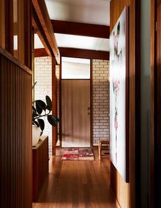 a hallway with wood paneling and white brick walls is seen through the doorway to another room