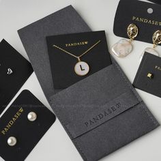 an assortment of jewelry is displayed on a white table with black tags and gold - plated necklaces