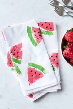 strawberries and watermelon printed napkins on a white table with silverware