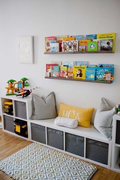 a room with some bookshelves and toys on the wall above it, along with two gray storage bins