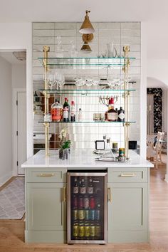 an open refrigerator in a kitchen next to a counter with bottles and glasses on it