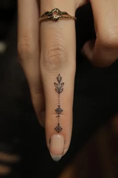 a woman's hand with a small tattoo on the middle finger and an arrow