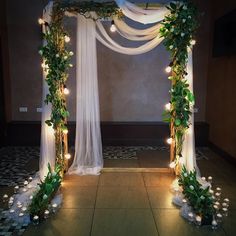 a wedding arch decorated with greenery and lights