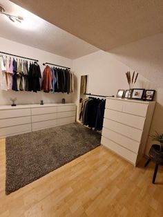 an empty room with clothes hanging on the wall and carpeted flooring in front of it