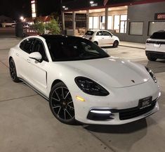 a white porsche panamera parked in front of a gas station with other cars