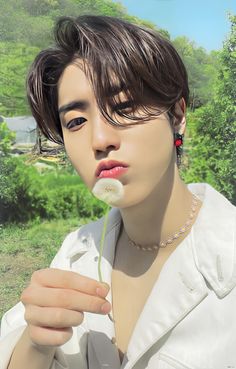 a young man holding a dandelion in his hand