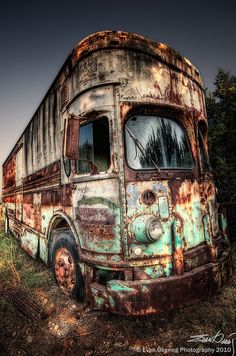 an old rusty bus sitting in the grass