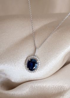 The beautiful blue color of this Sapphire gemstone makes this necklace a true show-stopper. We've set this 2.90ct Oval Cut Blue Sapphire in a White Gold pendant with a 0.29ctw Diamond Halo. Looking for a memorable birthday or anniversary gift? This bold pendant is perfect! Details: Gemstone: Sapphire Metal: 14K White Gold Chain, 18K White Gold Setting Gem Color: Blue Weight: 2.90ct Sapphire, 0.29ctw Diamond Gem Cut: Oval Quality: 100% Natural Gemstone 32 x 0.29ctw Diamond Halo Certified Blue Sapphire We can design any gemstone pendant specified in your style. Our inventory of gemstones makes it easy to design a masterpiece within your budget. Feel free to text us directly at 972-404-4499 to speak with a jewelry specialist. Want to see more photos📷 and videos 🎥 of our jewelry? Follow us o Formal Blue Oval Diamond Necklace, Blue Diamond Necklace For Formal Occasions, Luxury Blue Diamond Necklace For Formal Occasions, Formal Sapphire Pendant Diamond Necklace, Luxury Blue Diamond Necklace, Oval Sapphire Necklace With Brilliant Cut, Luxury Sapphire Necklace With Brilliant Cut, Exquisite Sapphire Necklaces, Sapphire Diamond Cut Necklace For Anniversary