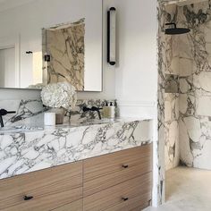 a bathroom with marble counter tops and wooden cabinets, along with two mirrors on the wall