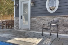 a chair sitting on the side of a house next to a swimming pool with chairs around it