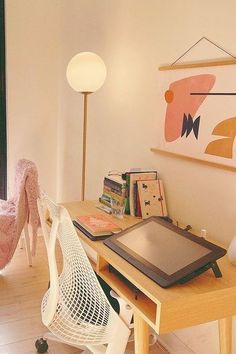 a desk with a tablet on it in front of a chair and lamp next to a window