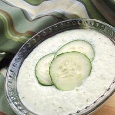 a cucumber in a bowl sitting on top of a table next to a knife