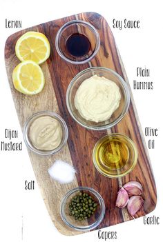 the ingredients to make an easy hummus recipe on a cutting board with lemons, capers and olives