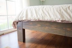 a bed sitting on top of a wooden floor next to a window