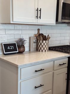 a kitchen counter with white cabinets and black appliances in the backround, next to an oven