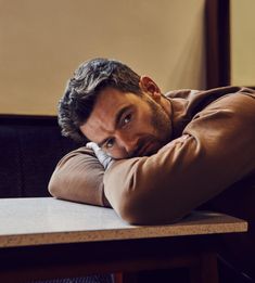 a man sitting at a table with his hands on his head and looking off to the side