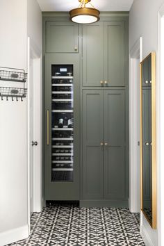 a wine cooler in the middle of a hallway with black and white tile flooring