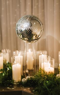 a disco ball surrounded by candles and greenery