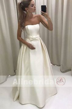 a woman taking a selfie in front of a mirror wearing a white wedding dress