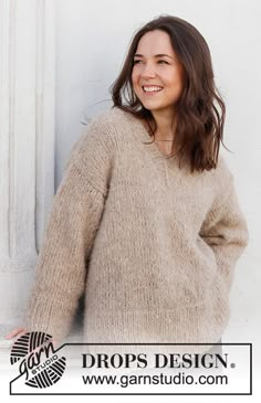 a woman standing in front of a white wall with her hands on her hips and smiling