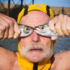 an older man holding up two fish in front of his eyes