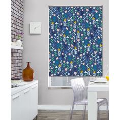 a kitchen with a window covered in blue and pink floral print curtains next to a white table