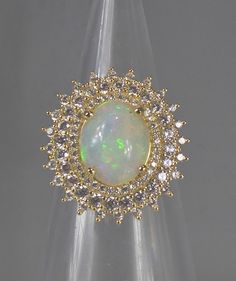 This stunning Ring boasts a beautiful Real Fiery Opal stone Surrounded by three stepped halo's set with clear cubic zirconia's that sparkle like real diamonds all set in a Silver and Gold base metal design. The intricate craftsmanship is apparent in the detailed metalwork, creating a unique and eye-catching piece of fine jewellery. The Ring is made of 925 metal purity and Gold plating. Perfect for any occasion. Add this elegant piece to your collection today. Front Ring Panel  Measures 2cm x 2.2 Elegant Multi-stone Opal Ring For Collectors, Antique Gold Opal Ring With Multi-stones, Luxury Multi-stone Opal Ring For Gift, Victorian Multi-stone Opal Ring As Gift, Luxury Multi-stone Opal Ring In 14k Gold, Halo Setting, Opal Stone, Fine Jewellery, Metal Design