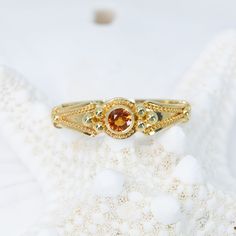 This 18K granulated gold ring adds a classic touch to any ensemble. A simple and elegant design combined with a timeless look make this Orange Classical Ring the perfect accessory for a variety of occasions. 18KY granulated ring with .15ct orange sapphire. Size: 8.25, but each ring comes with free sizing and FREE SHIPPING! Unsure what ring size you are? It's always best to be sized by a professional jeweler, but if that is not available, you can use our special Ring Sizing Chart. Gold Yellow Sapphire Birthstone Ring, Yellow Sapphire Ring With Center Stone In Yellow Gold, Heirloom Gold Sapphire Ring With Round Band, Yellow Gold Milgrain Round Ring, Yellow Gold Milgrain Ring, Gold Round Yellow Sapphire Ring, Gold Yellow Sapphire Round Ring, Gold Yellow Sapphire Ring, Round, Gold Yellow Sapphire Promise Ring